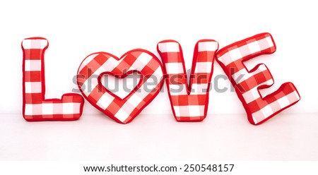 Funny love word of plush red letters on white background. Full plaid textile. February 14, Valentine's Day concept shot with text space. Top view. High resolution
