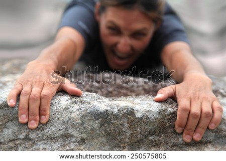 Climber hanging on to the edge of a rock.   Royalty-Free Stock Photo #250575805