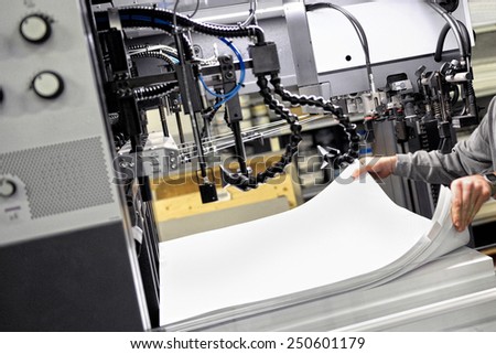 Worker Preparing Large White Papers for Print at the Printing Machine