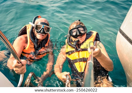 Senior happy couple using selfie stick in tropical sea excursion - Boat trip snorkeling in exotic scenarios - Concept of active elderly and fun around the world - Soft vintage filtered look Royalty-Free Stock Photo #250626022
