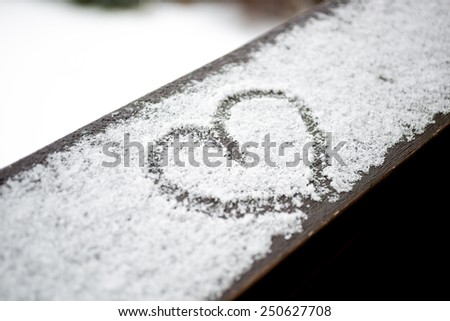 Closeup photo of heart drawn on white snow
