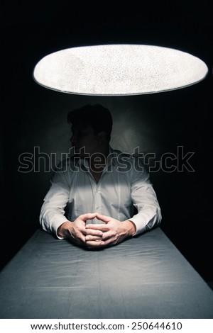 Man in a dark room illuminated only by a light coming from a lamp no face seen Royalty-Free Stock Photo #250644610