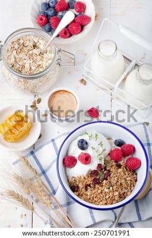 Healthy breakfast. Granola, muesli with pumpkin seeds, honey, yogurt and fresh berries in a ceramic bowl  with a cup of coffee on white background. Copy space