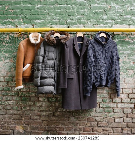Men trendy clothing on hangers on grunge brick wall. Concept background