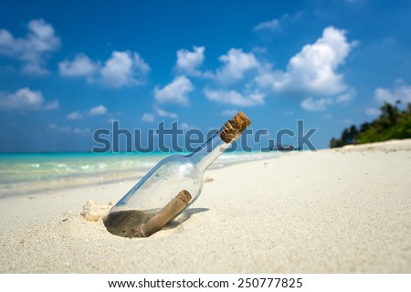 Message in a bottle washed ashore on a tropical beach. Royalty-Free Stock Photo #250777825