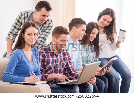 Education and people concept. Group of students are sitting on the sofa, with laptop, book and coffee.
