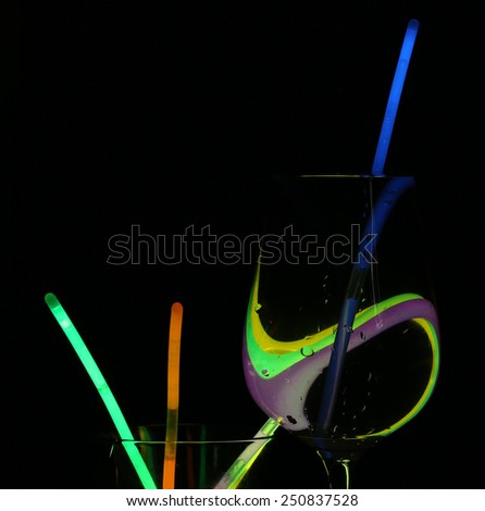 Champagne glass in neon light with glowing neon sticks, abstract colorful background