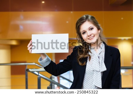 Young beautiful girl holding empty white card and smiling