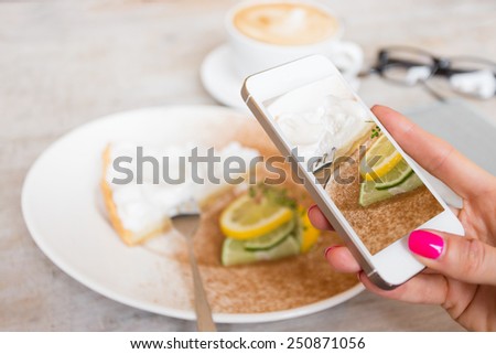 Woman taking photo of her cake in cafe with mobile phone