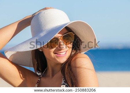 smiling summer woman on beach with sunglasses and floppy hat