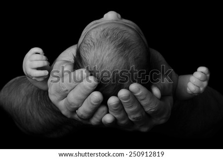 Newborn baby in the arms of his father, close-up. black and white photography