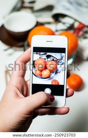 Woman's hand photographing everyday still life on working table with smartphone