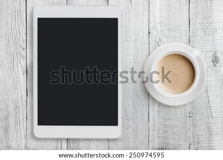 Tablet pc looking like ipad mini on table with coffee cup  Royalty-Free Stock Photo #250974595