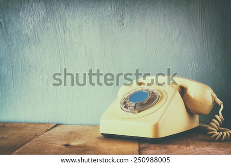 Retro telephone on wooden table. filtered image with faded retro style
