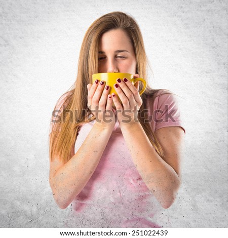 Pretty girl holding a cup of coffee over textured background 