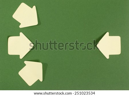 Paper arrows pointing inward. Yellow post it arrows on green background facing in.