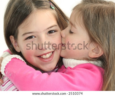 little girl giving big sister a kiss on the cheek