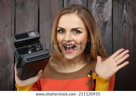 beautiful girl with old retro camera in his hands on the wooden background