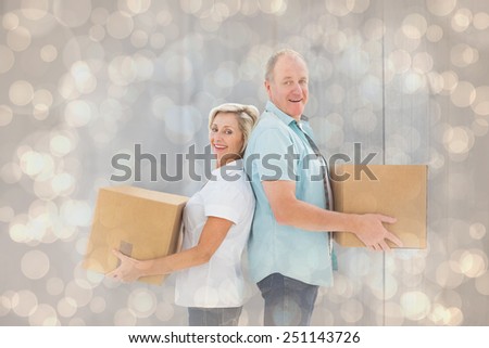 Happy older couple holding moving boxes against light glowing dots design pattern