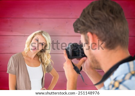 Man taking photo of his girlfriend sticking her tongue out against wooden planks background