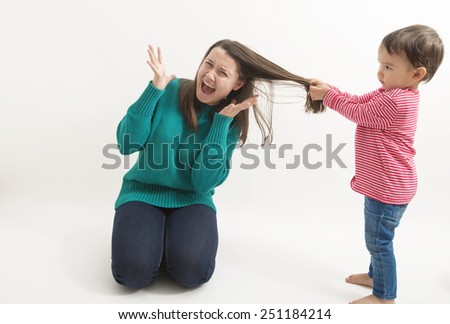 A little girl pulls her older sister hair Royalty-Free Stock Photo #251184214