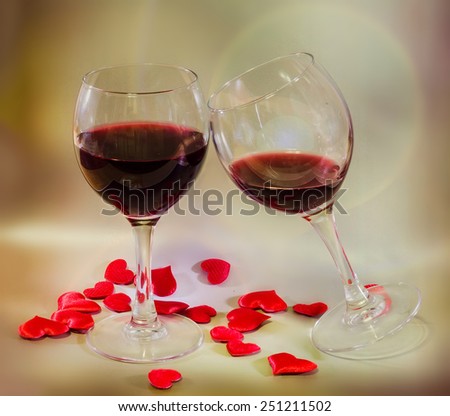 Transparent glasses with red wine and textile red valentine hearts, background with lights, close up.