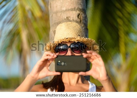 Woman on caribbean tropical vacation taking photos with smartphone camera. Brunette tourist on travel to Riviera Maya, Mexico.