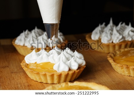 A process of decorating lemon tartlets with meringue icing