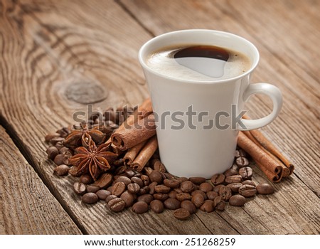 Coffee cup, anise stars, cinnamon sticks and coffee beans on old boards.