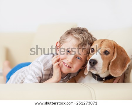 Happy boy with his dog lying on sofa