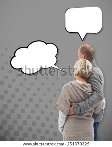 Happy mature couple in winter clothes against grey