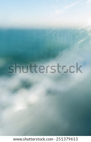Slurred steamy glass and small water droplets on the endless blue ocean background