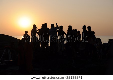 Silhouette of group of people dancing at sunset near the sea