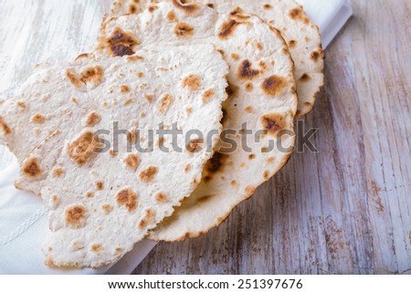 Homemade whole wheat flour tortillas on a wooden table. Unleavened bread.