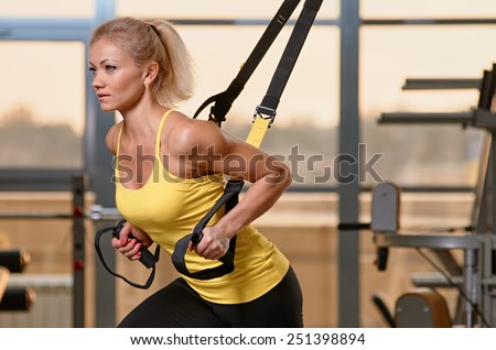 Young attractive woman training with htrx fitness straps in the gym's studio Royalty-Free Stock Photo #251398894
