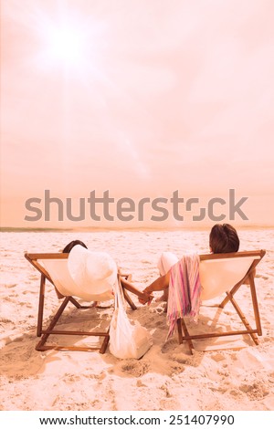 Couple looking ocean on their deck chairs on beach