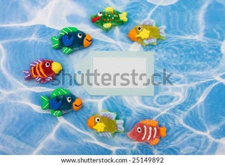 A large group of colourful fish with blank gift tag sitting on blue water background, colourful fish