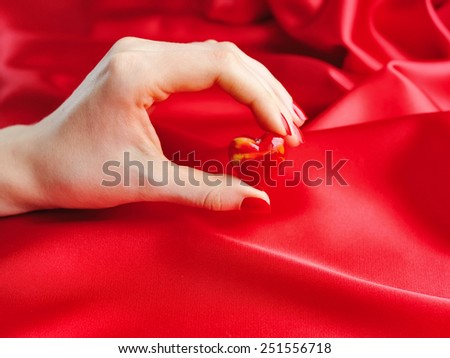 Decorative heart in female hand against a background of red silk