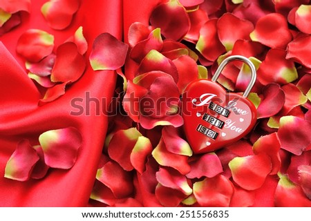 Padlock heart-shape on a background of red petals and satin