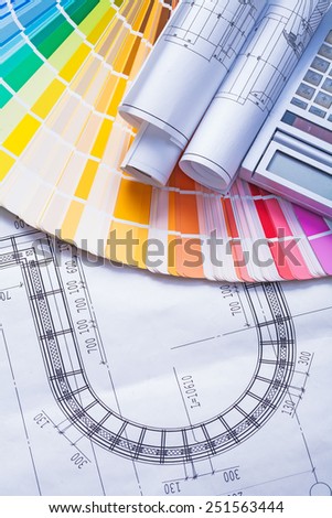 rolled up blueprints on color palette and calculator 