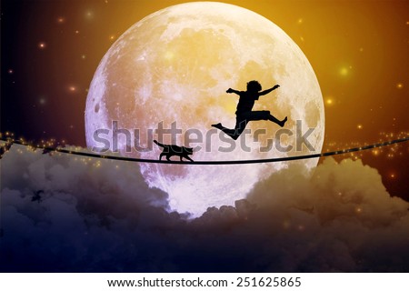 Happy boy teenager and cat jumping on a tight rope above clouds with moonlight moon background. Happiness friendship care free concept. Elements of this image furnished by NASA