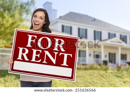Excited Mixed Race Female Holding For Rent Sign In Front of Beautiful House.