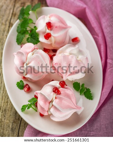 Meringue cookies in bowl with cream and pomegranate seeds , selective focus