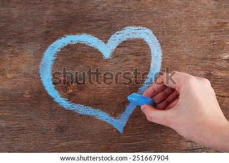 Hand draws heart of chalk on wooden board  