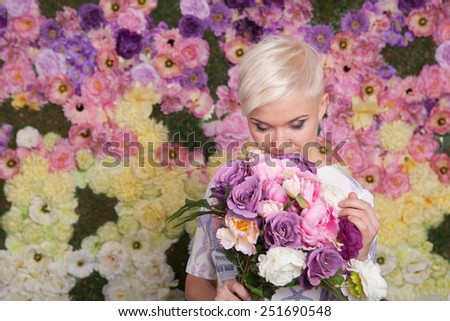 Beautiful blond woman holding flowers, looking up, short haircut 