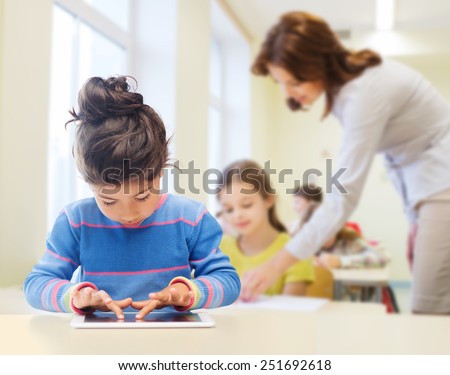 education, elementary school, technology and children concept - little student girl with tablet pc over classroom and teacher background Royalty-Free Stock Photo #251692618