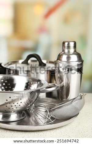 Stainless steel kitchenware on table, on light background
