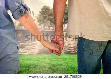 Couple holding hands in park against sunny day by the river