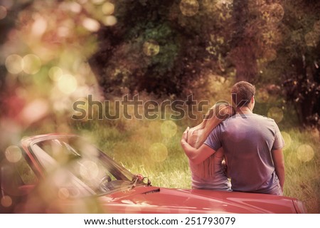 Loving couple admiring nature while leaning on their cabriolet on a sunny day