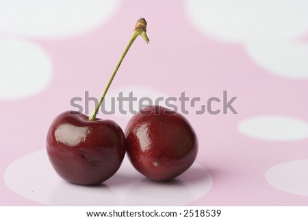 2 cherries on pink polka dot background